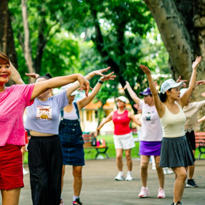 Grupo de pessoas praticando exercícios ao ar livre em um parque urbano.