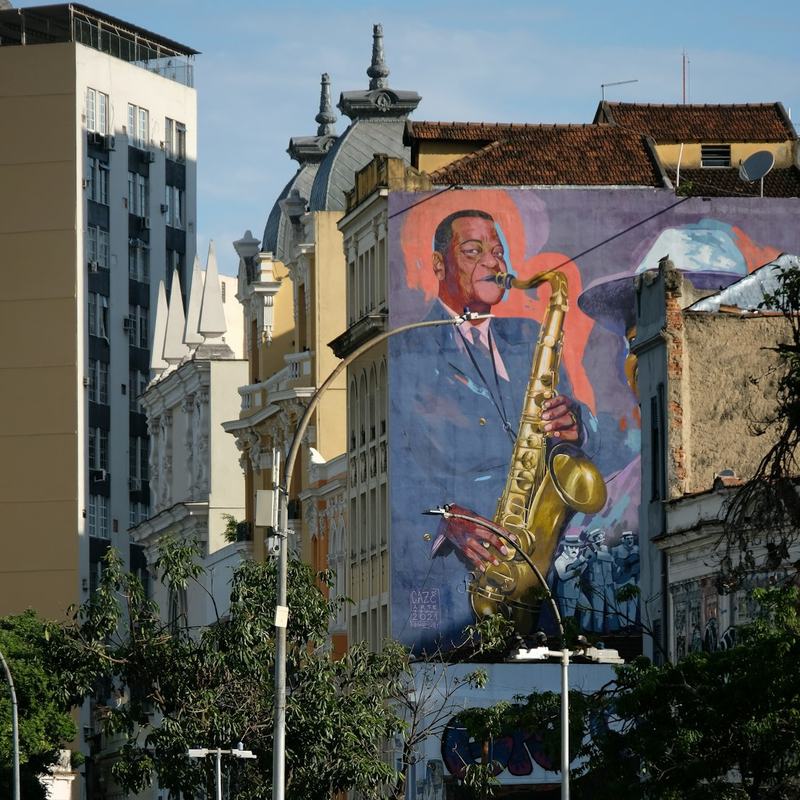 Mural urbano de grandes dimensões retratando um músico tocando saxofone.
